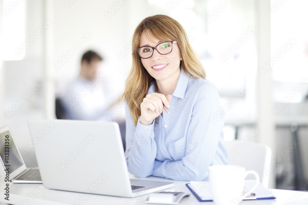Portrait of an executive investment advisor professional woman sitting at office and working on laptop. Portrait of an executive investment advisor professional woman sitting at office and working on laptop.