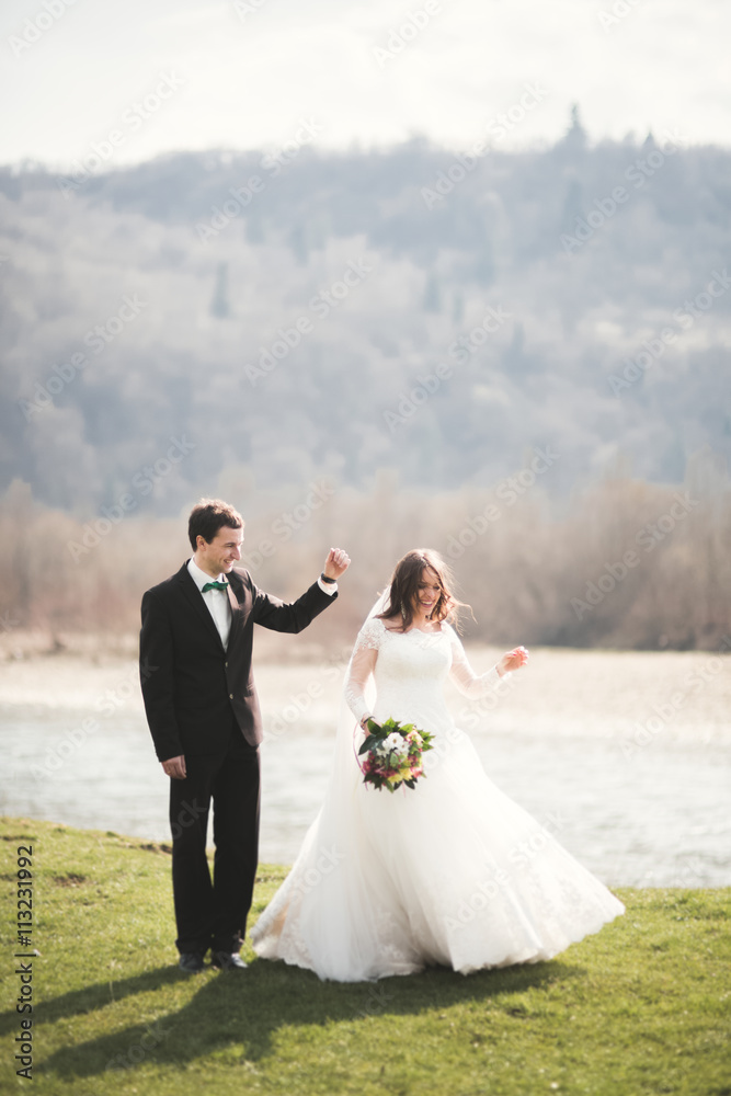 Beautiful wedding couple, bride, groom posing and walking in field against the background of high mountains
