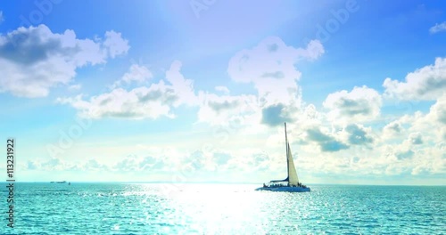 4K Catamaran BoatSailing on Tropical Turquoise Blue Sea, Sun and Clouds in Backg photo