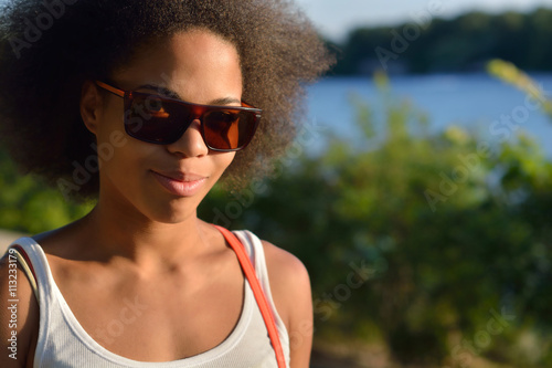 Young beautiful, sexy black girl posing and flirting in the summer park near the old building and water