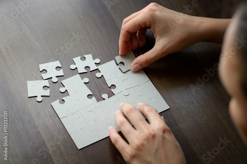 Female hands on a wooden office desk pick puzzle