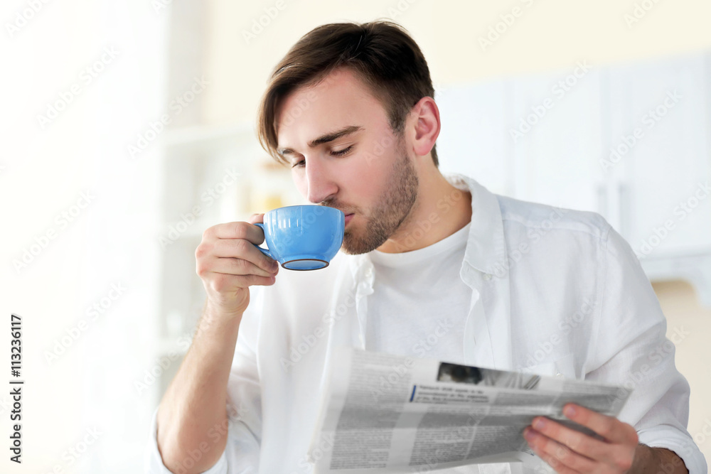 Young handsome man with cup of coffee in the kitchen Young handsome man with cup of coffee in the kitchen