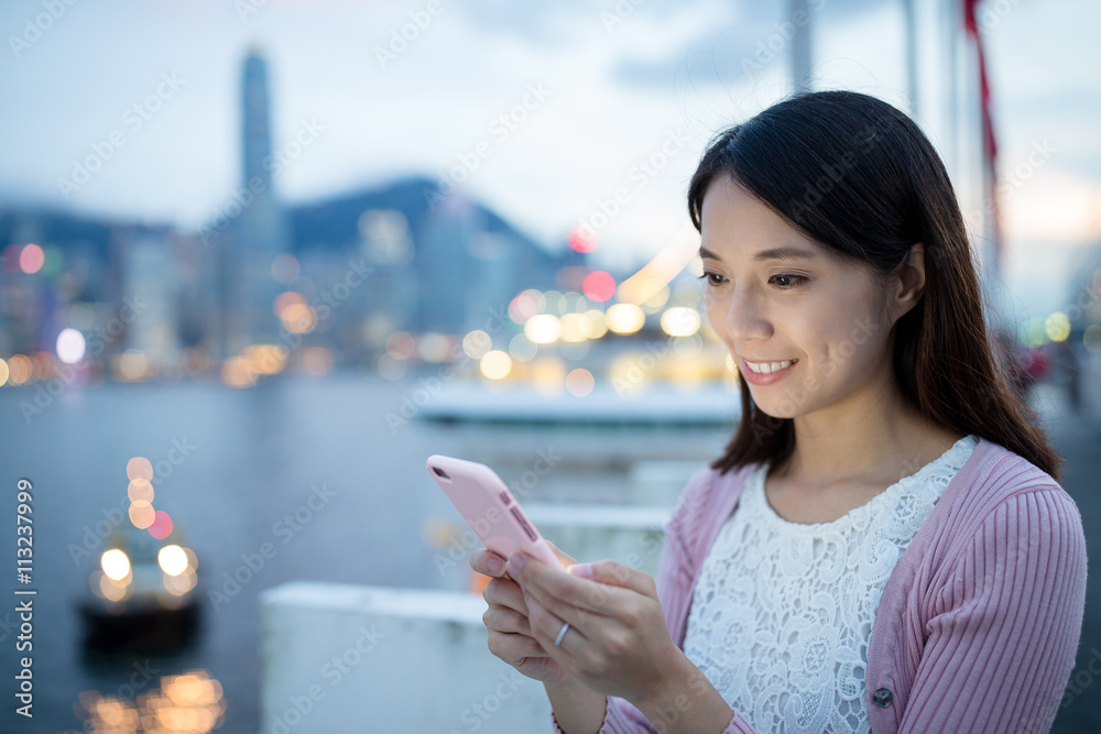 Asian woman sending sms text message on mobile phone Asian woman sending sms text message on mobile phone