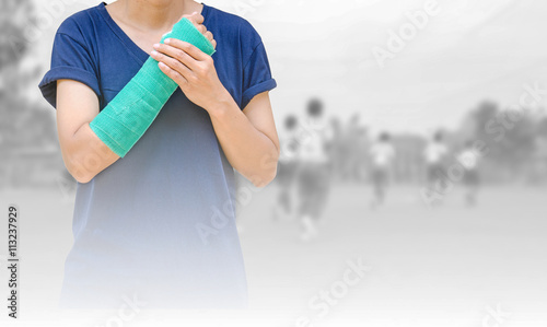 broken arm with green cast on blurred background kid soccer play