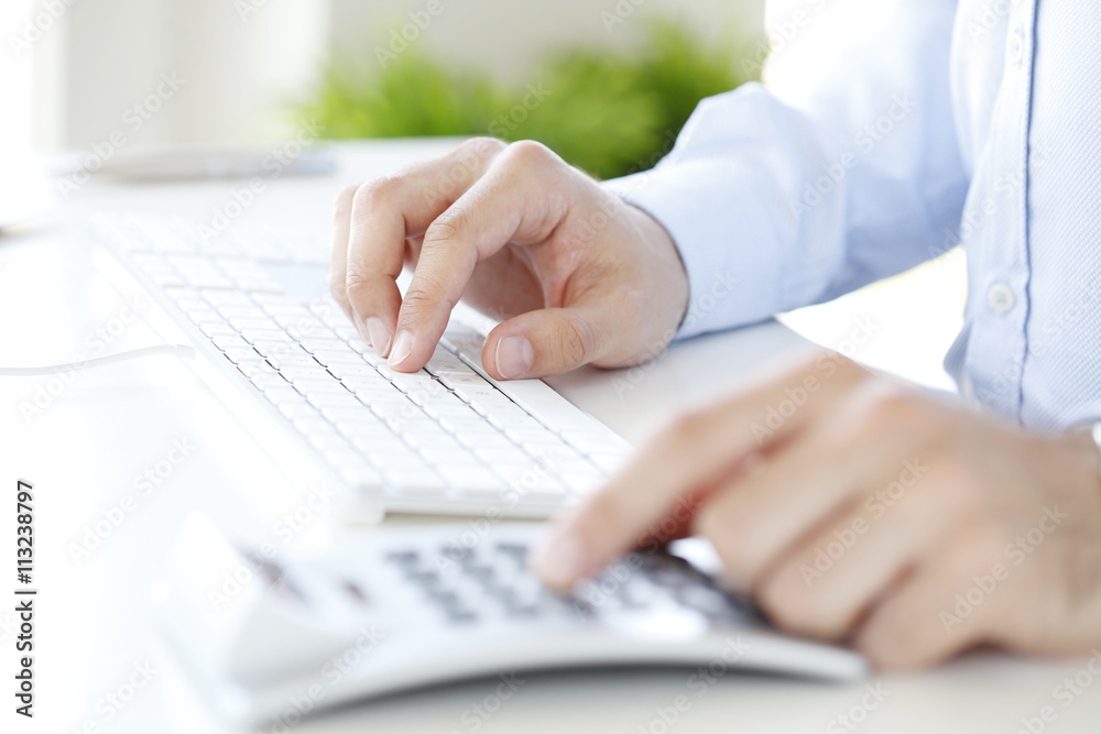 Calculating expenses. Close-up of investment advisor calculating expenses while sitting at office in front of computer Calculating expenses. Close-up of investment advisor calculating expenses while sitting at office in front of computer