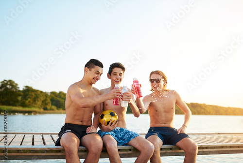 Three happy teenage boys toasting each other