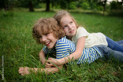 Bbrother and sister play on a green lawn