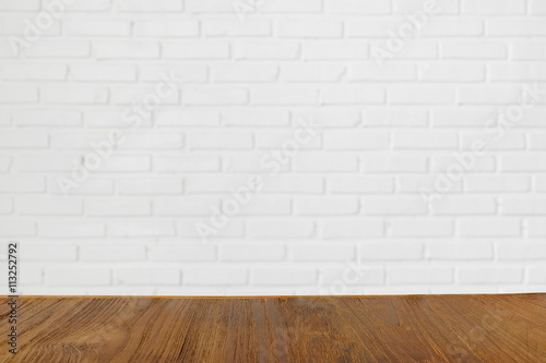 Wooden table with blurred white birck wall on the background, can be used for product montage