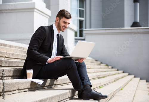 Positive handsome businessman sitting on the footsteps