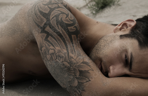 Samolepka Handsome male lying on the sand