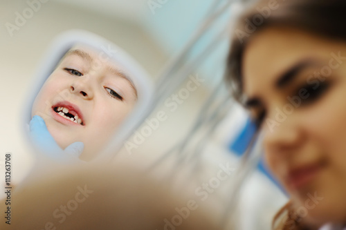 baby girl examines teeth in a dental mirror