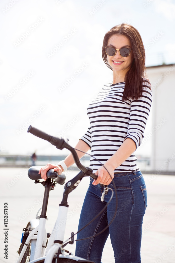 Confident woman standing near a bike