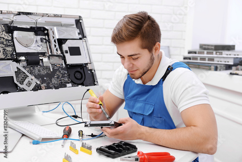 Young repairer working with soldering iron in service center