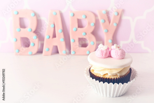 Word "Baby" with cupcake on bright background
