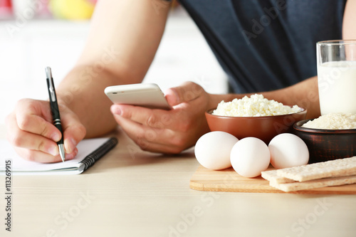 Man counting calories on table photo
