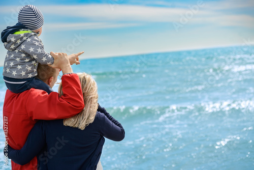 Back view of a happy family at tropical beach on summer vacation