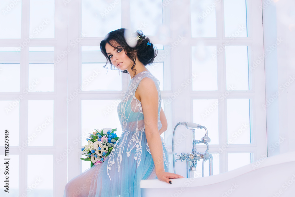 Beautiful brunette bride in wedding dress colors, serenity, sitting on the bathtub, dreaming about the groom.