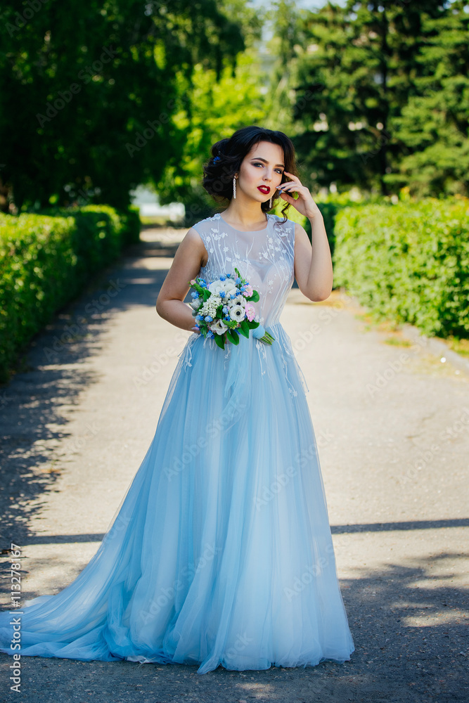 Beautiful brunette bride in a luxurious wedding dress in the garden. Color wedding dresses serenity. Beautiful brunette bride in a luxurious wedding dress in the garden. Color wedding dresses serenity.