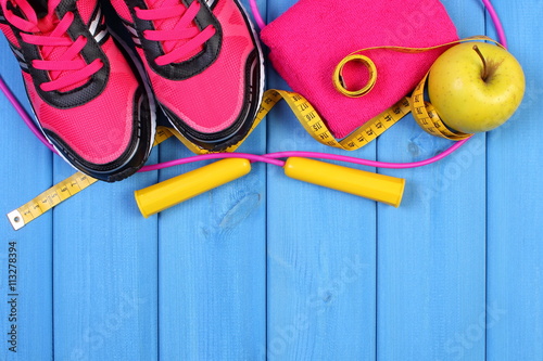 Pair of sport shoes, fresh apple and accessories for fitness on blue boards, copy space for text