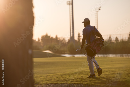 golfer walking and carrying golf bag at beautiful sunset