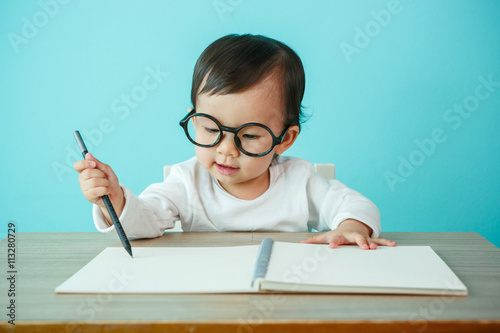 Portrait of an adorable baby girl wearing glasses on the table ( photo