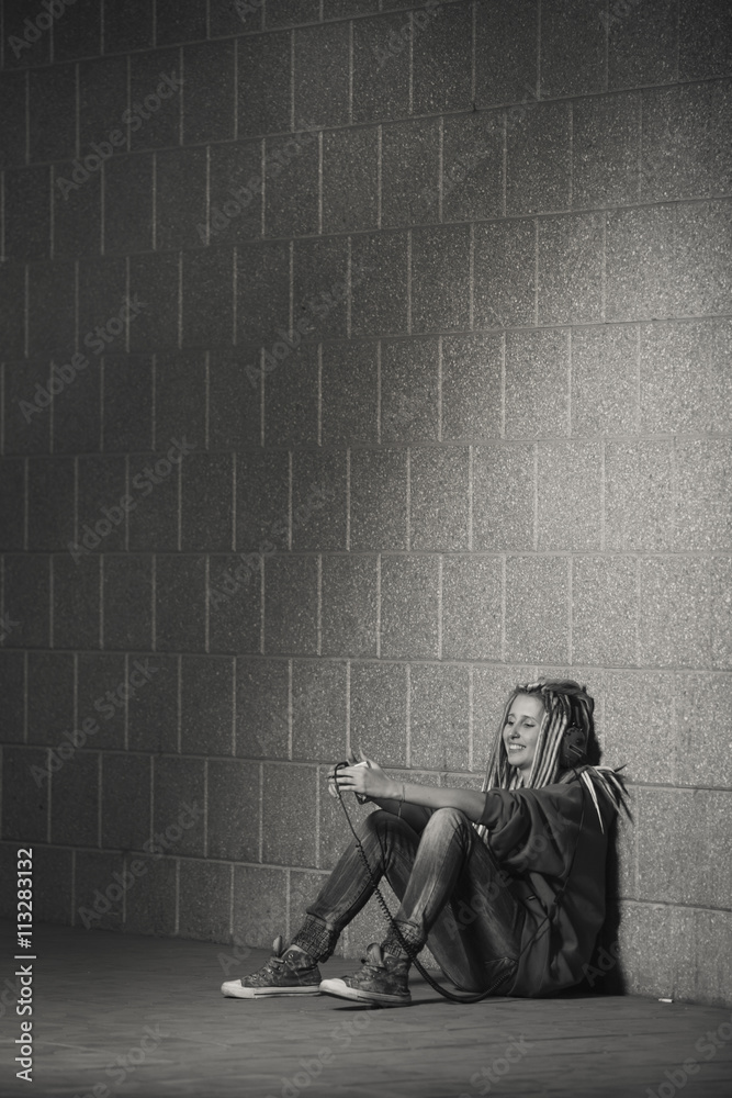 Depressed young teenage girl in hood sitting down on road in th city. Alone in the big city. Depressed young teenage girl in hood sitting down on road in th city. Alone in the big city.