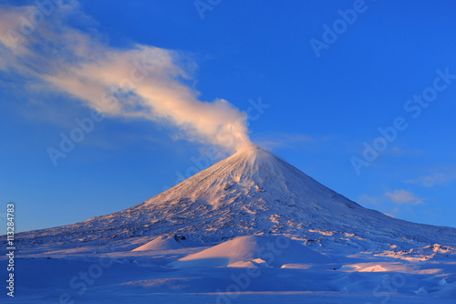 Winter volcanic landscape of Kamchatka Peninsula  view of erupting active Klyuchevskaya Sopka at sunrise. Eurasia  Russian Far East  Kamchatka Region  Klyuchevskaya Group of Volcanoes.