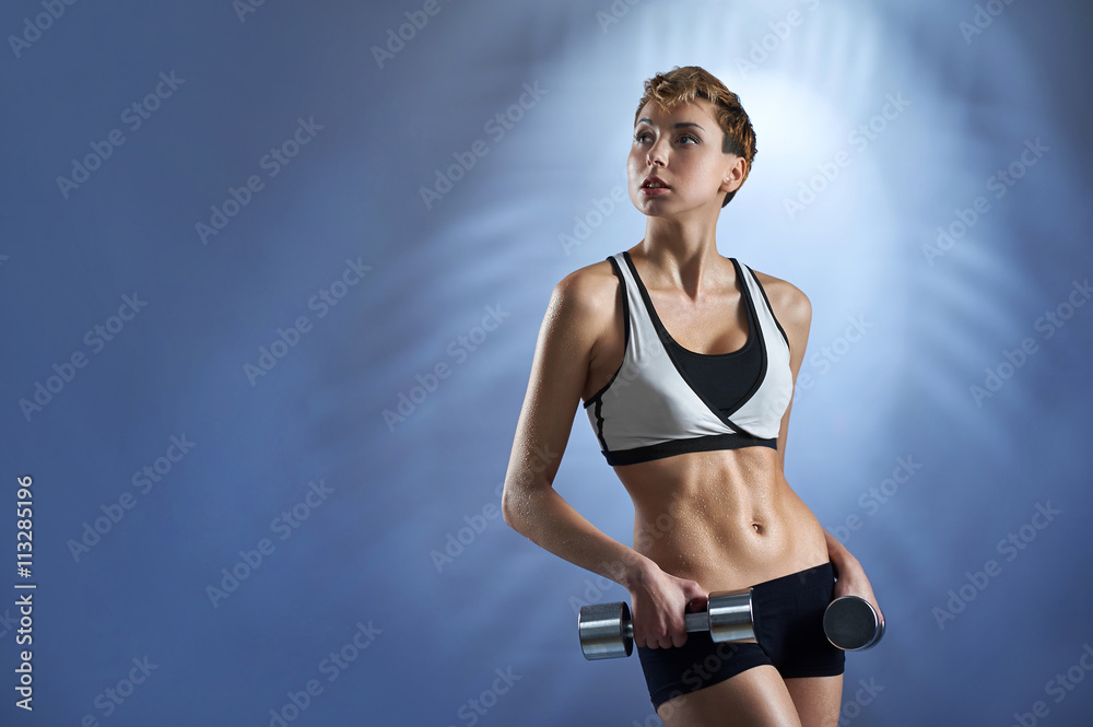 Pursuing her dreams. Studio portrait of a young short haired sporty woman wearing sportswear holding dumbbells looking away copyspace on the side Pursuing her dreams. Studio portrait of a young short haired sporty woman wearing sportswear holding dumbbells looking away copyspace on the side