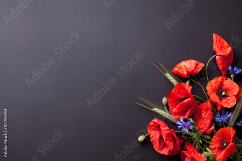 Heads of red poppies, rye and cornflowers on black background fl