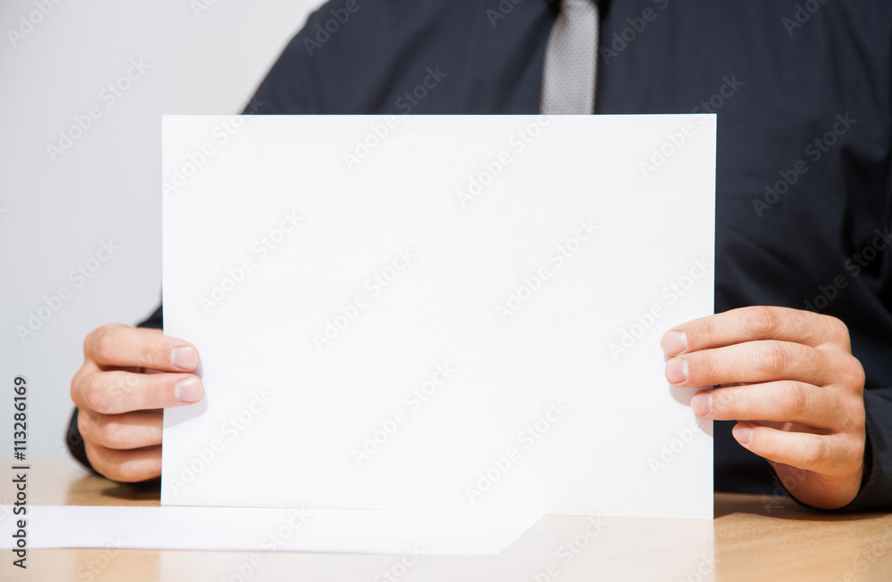 Businessman holding an empty sheet of paper Businessman holding an empty sheet of paper