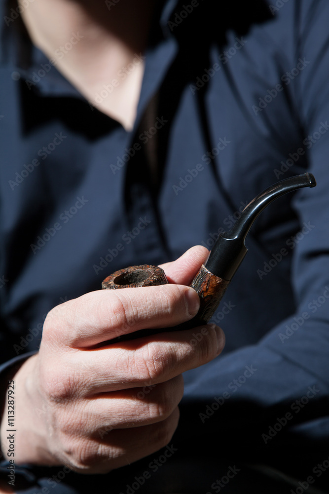 Unrecognizable young man with tobacco pipe