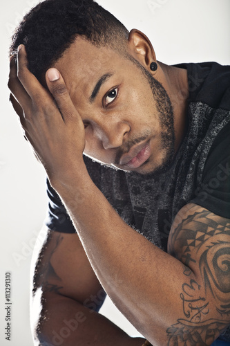 African male model in casual stylish clothing sitting and leaning on his hand looking serious