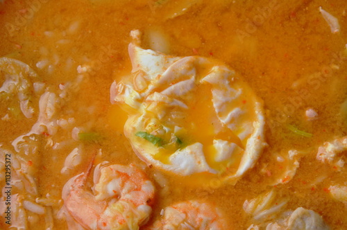 rice porridge topping creamy yolk egg and seafood in spicy soup on bowl