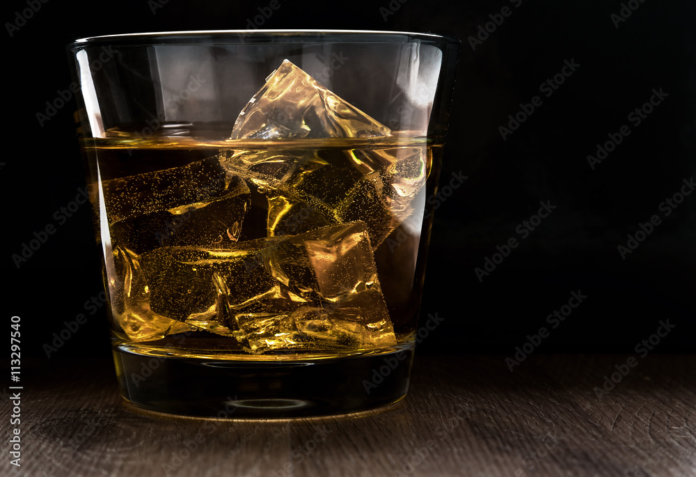Glass of whiskey and ice on a wooden table Glass of whiskey and ice on a wooden table