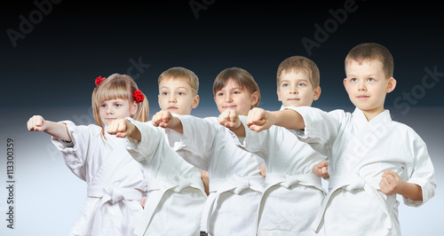 Five little athletes hit a punch on a gradient background