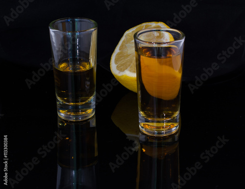 Two glasses filled with alcohol drink and a half of a lemon