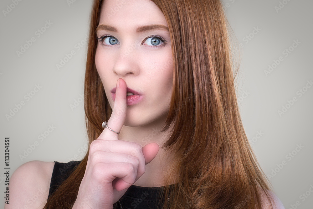 Beautiful redhead girl presses a finger to the lips Beautiful redhead girl presses a finger to the lips