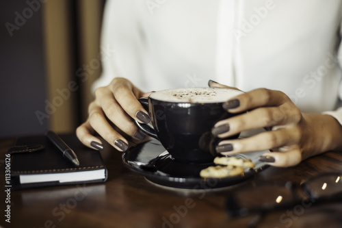 close up of a woman drinking coffee by a wooden table  