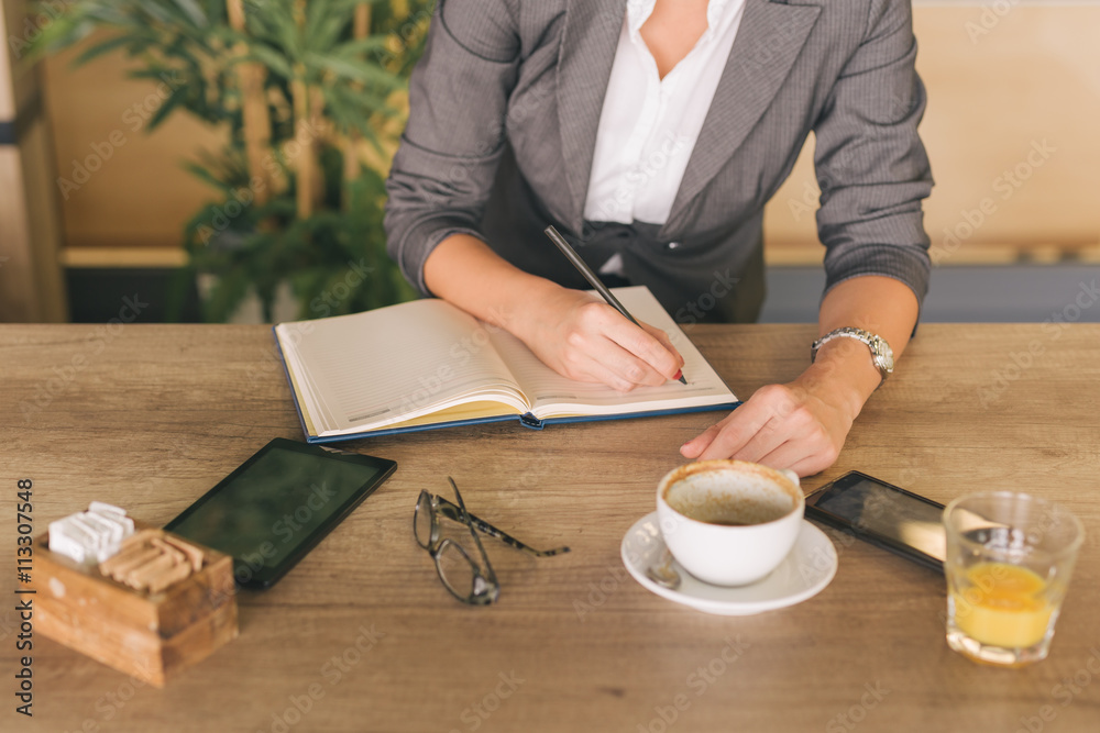 Business woman writing in planner in cafeteria Business woman writing in planner in cafeteria