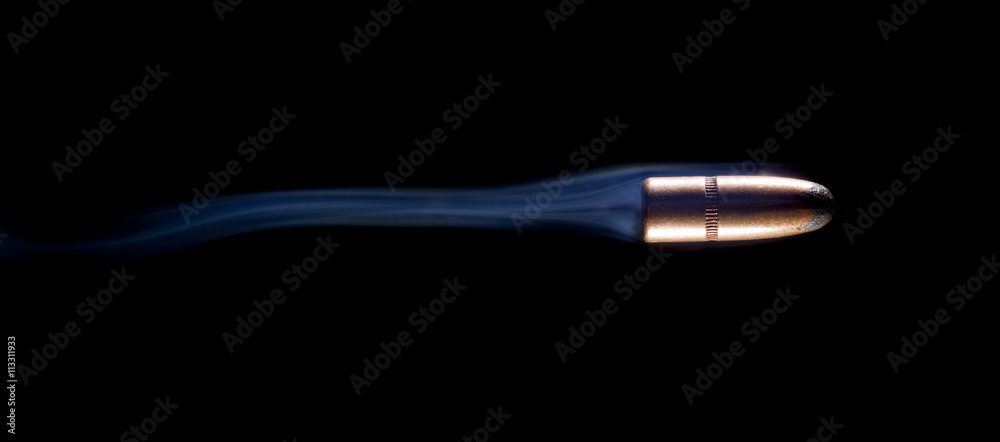 Smoking fast copper jacketed bullet streaking across a black background Smoking fast copper jacketed bullet streaking across a black background