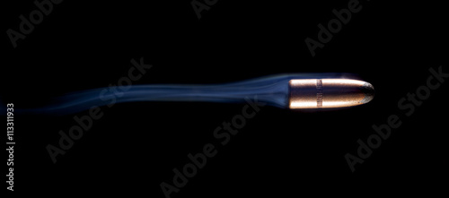 Smoking fast copper jacketed bullet streaking across a black background
