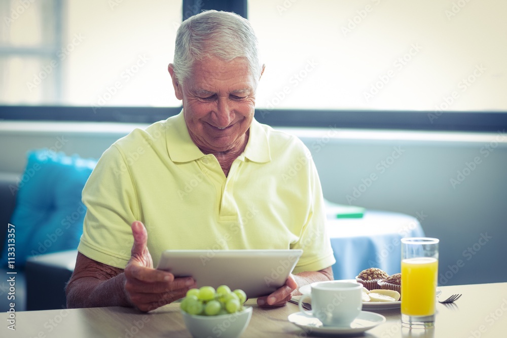 Senior man using digital tablet while having breakfast Senior man using digital tablet while having breakfast