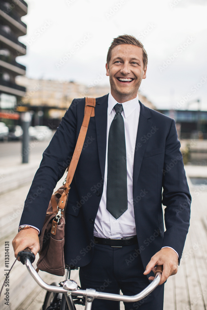 Smiling businessman standing with bicycle in city Smiling businessman standing with bicycle in city