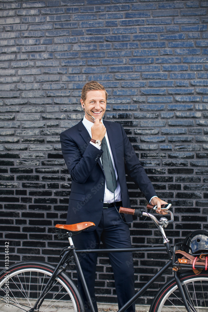 Portrait of happy businessman talking on mobile phone while standing on sidewalk with bicycle Portrait of happy businessman talking on mobile phone while standing on sidewalk with bicycle