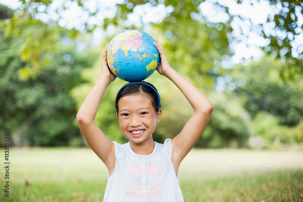 Portrait of smiling girl carrying a globe on her head Portrait of smiling girl carrying a globe on her head