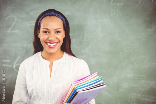Photo Portrait of smiling school teacher holding books in classroom