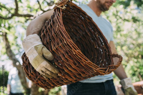 Midsection of man carrying wicker basket at yard