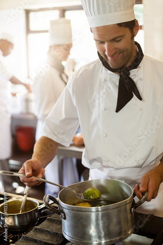 Fototapeta Naklejka Na Ścianę i Meble -  Smiling head chef stirring in pot