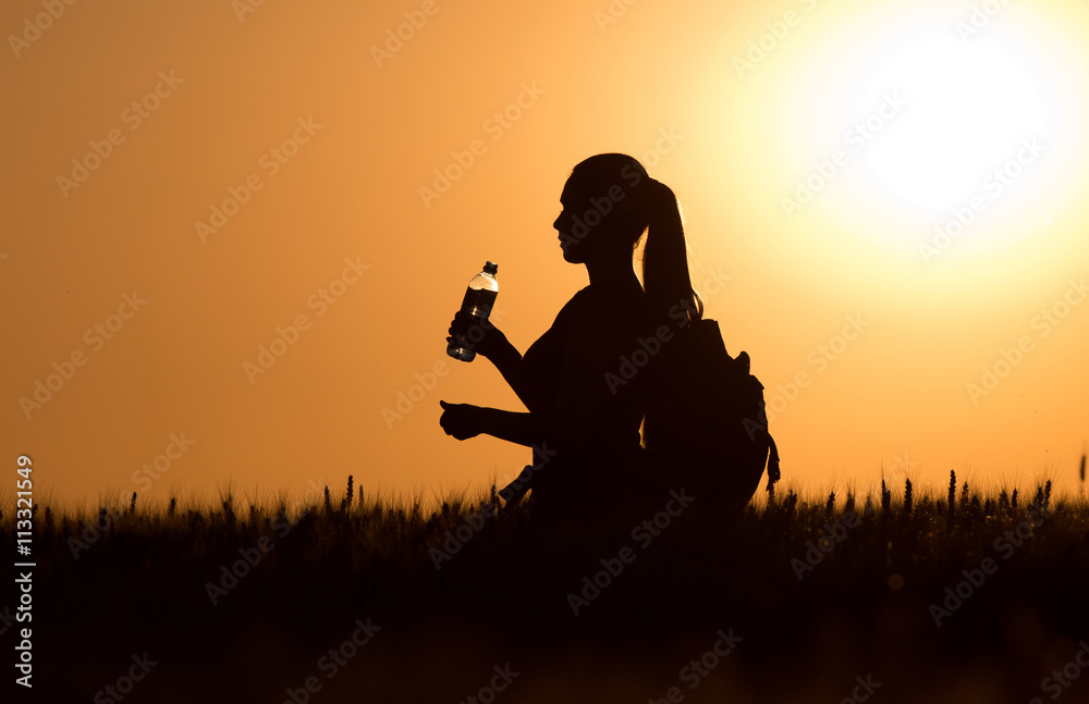 Silhouette of woman with backpack and bottle of water