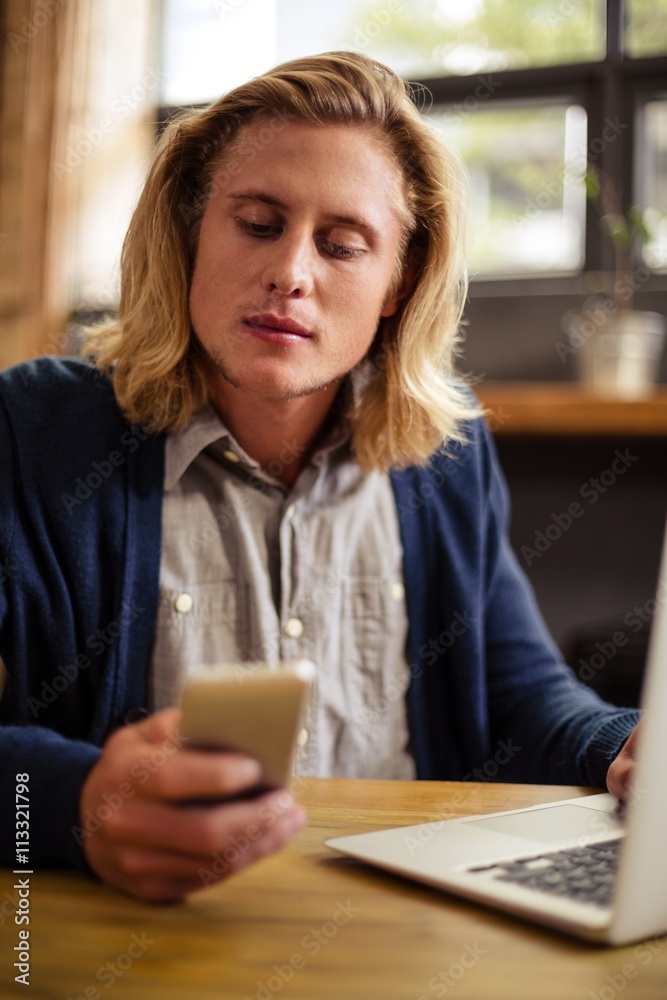 Hipster using a laptop and a smartphone Hipster using a laptop and a smartphone